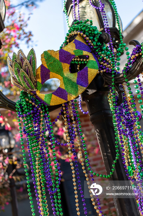 Outdoor Mardi Gras beads and mask on light post in sunshine