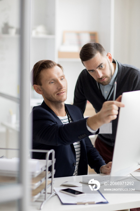 Portrait of two professionals looking at computer screen while working in modern office