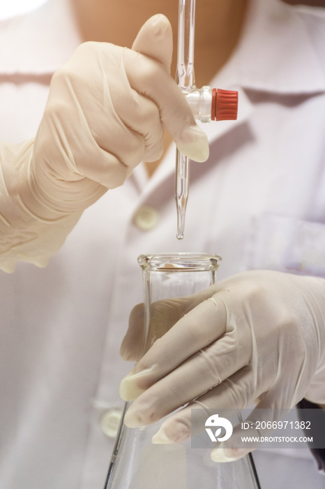 close up of hands are holding the burette and flask in chemistry laboratory.