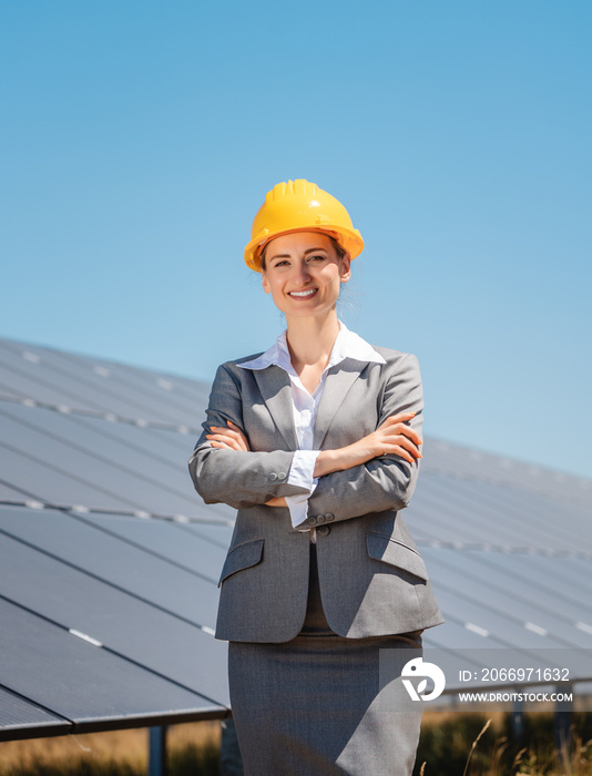 Woman investor in clean energy standing in front of solar panels