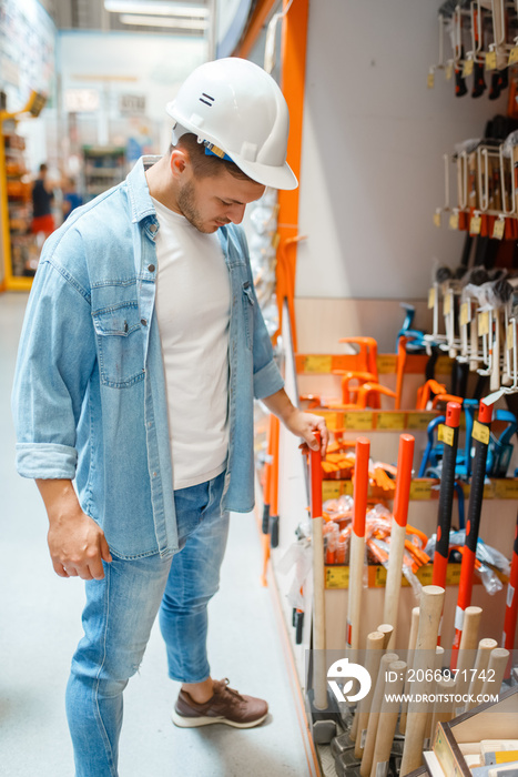 Male buyer choosing hammer in hardware store