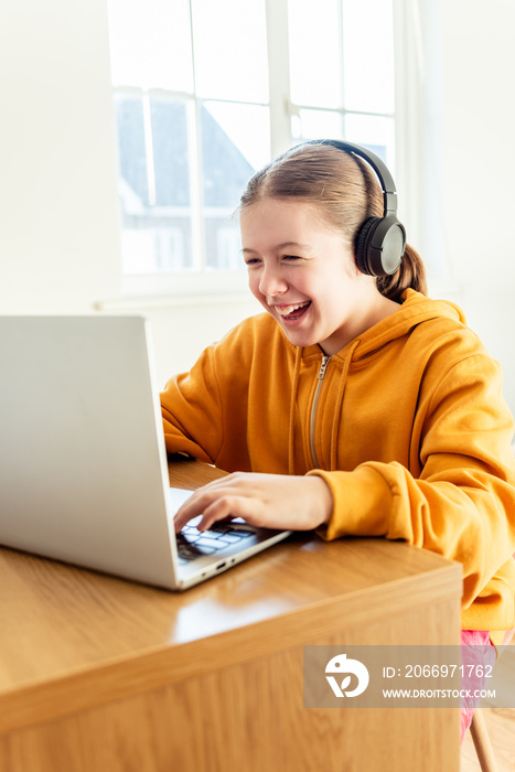 School age girl is home schooling using laptop during self isolation at her bedroom, online education, doing homework, distance learning