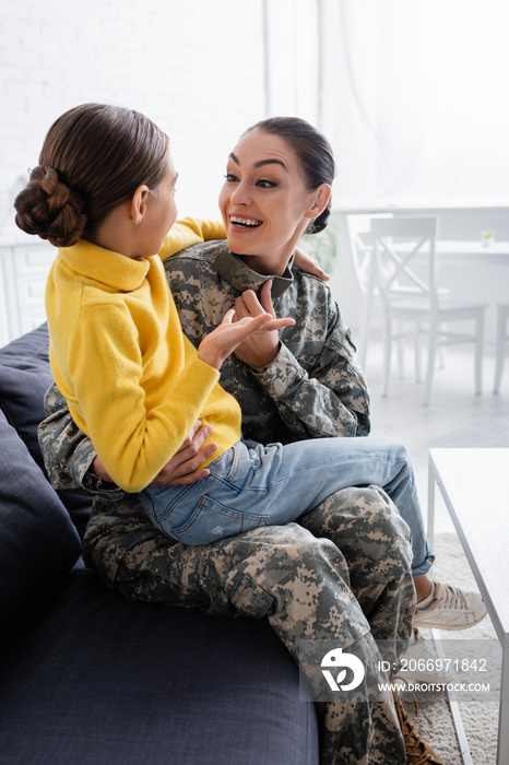 Positive woman in military uniform talking to daughter at home