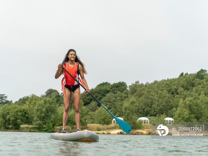 Smiling woman paddleboarding on lake