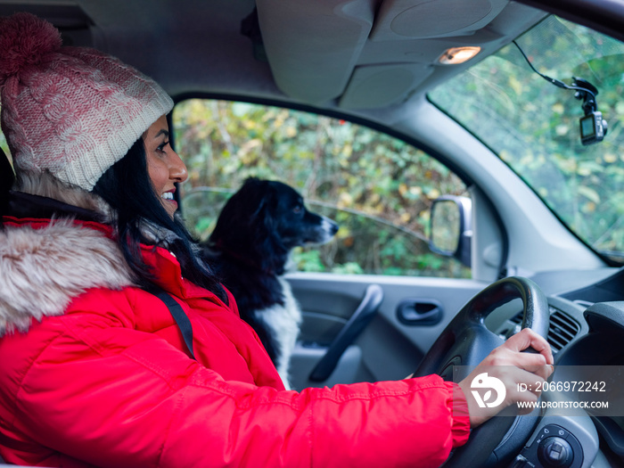 Woman driving car with dog in passenger seat