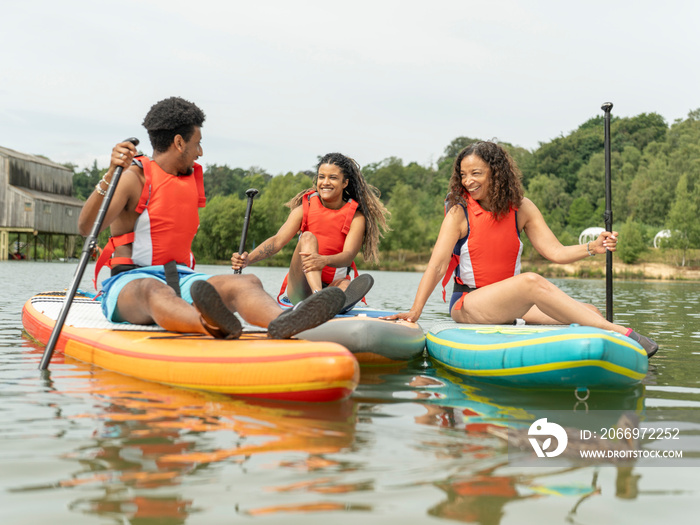 Friends having fun while paddleboarding on lake