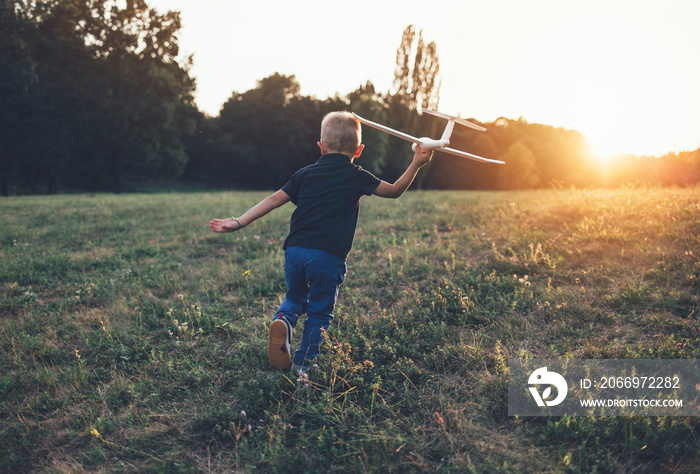 Rear view of boy running with glider airplane model for takeoff