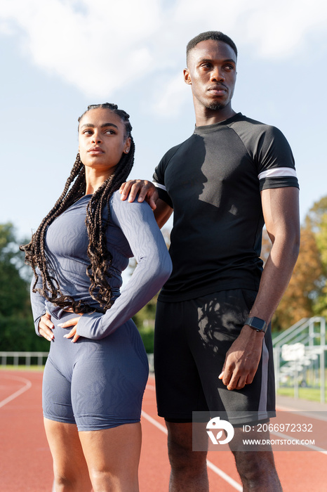 Portrait of couple of athletes standing at sports track