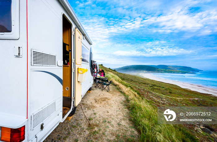 Motorhome RV and campervan are parked on a beach.