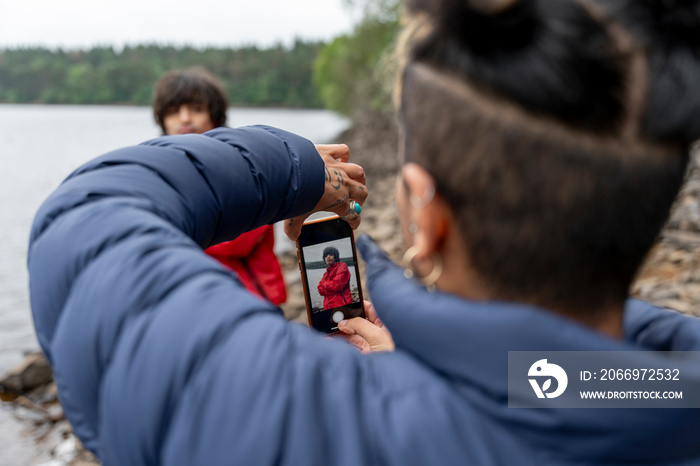 Mother photographing son by lake on hike