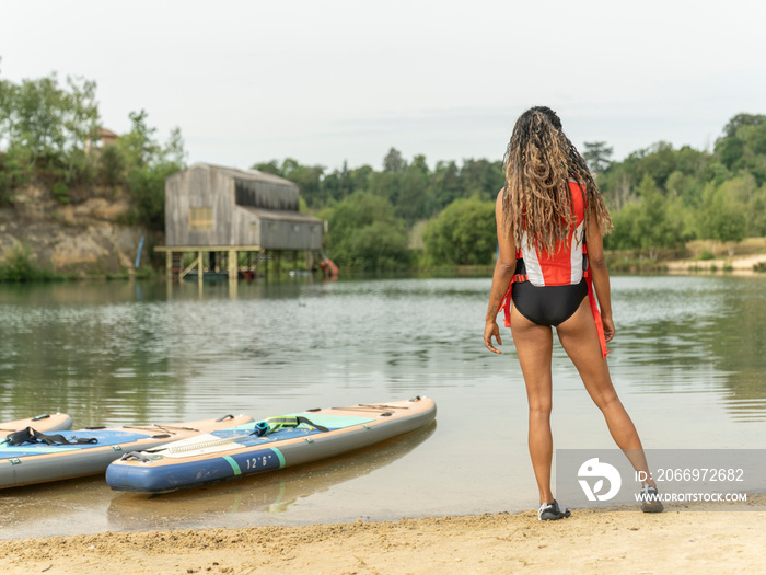 Rear view of woman looking at lake before paddleboarding