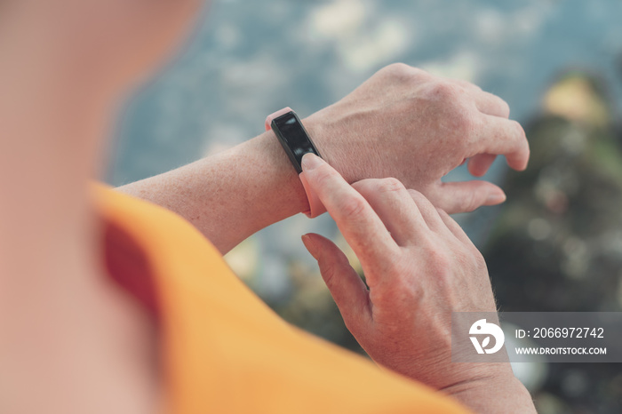 Female hiker using smart bracelet during trekking in nature