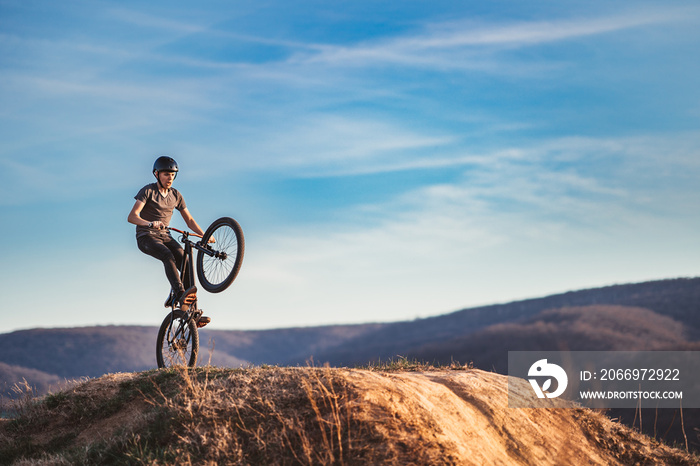 Young man on a mountain bike performing a dirt jump