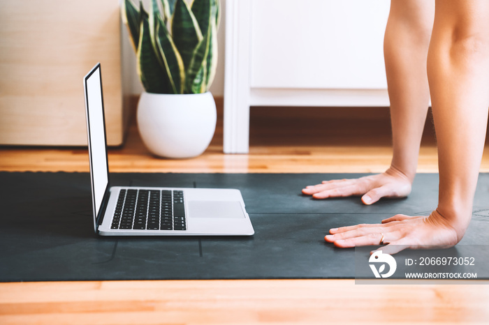 Closeup of female palms on yoga mat with laptop.