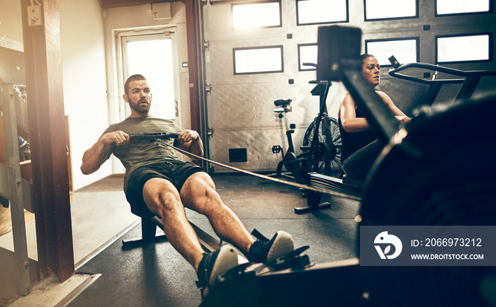 Fit man exercising on a rowing machine at the gym