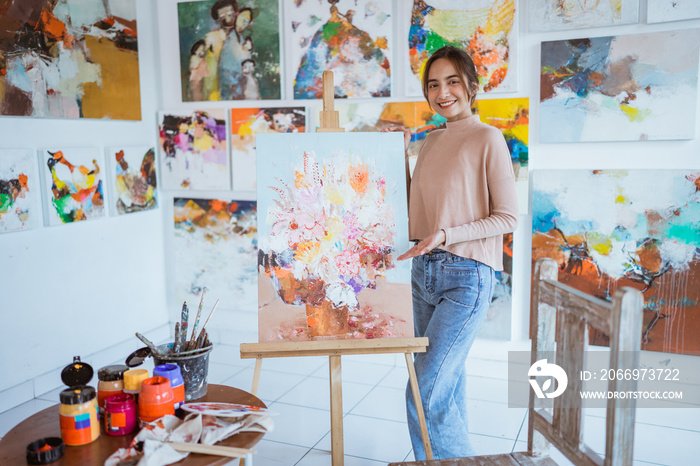 asian female painter painting on canvas in her workshop