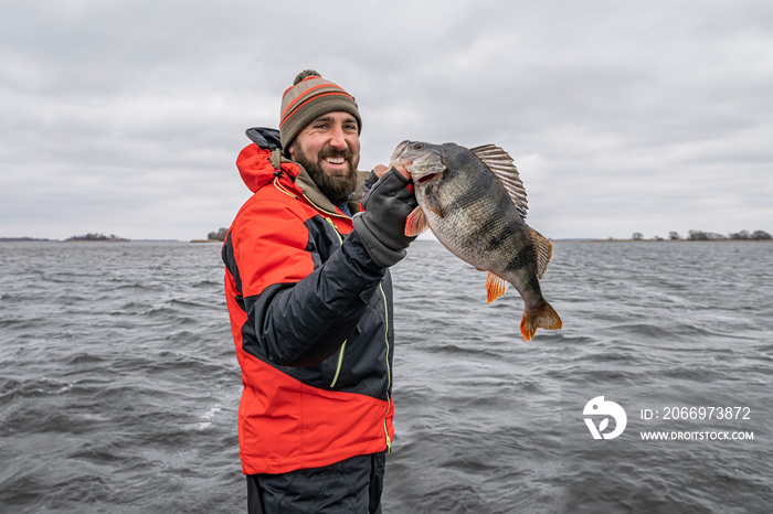 Happy fisherman with big perch fish trophy at boat