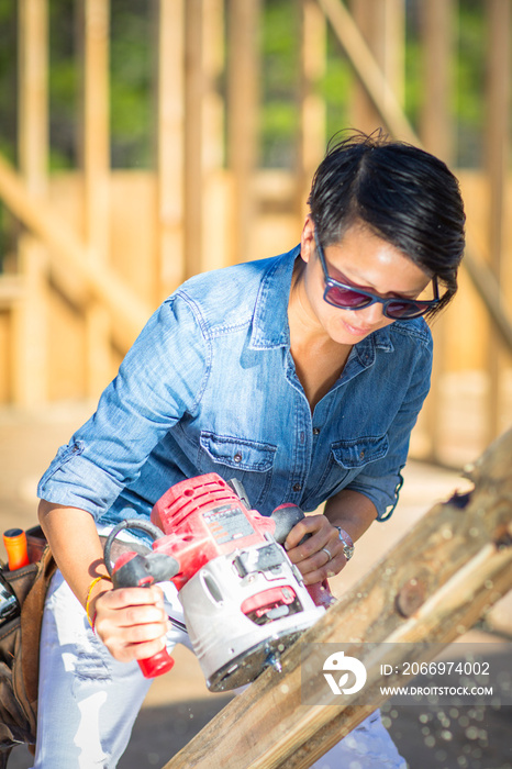 Mid adult woman using power tool, building her own home