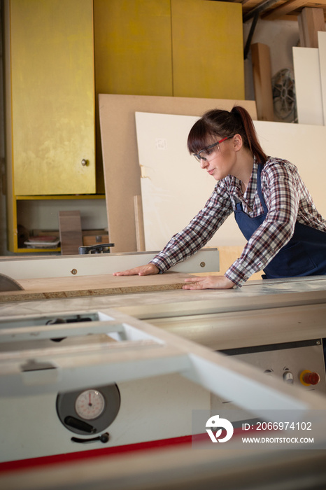 Craftswoman working on the sliding table saw in the carpentry workshop