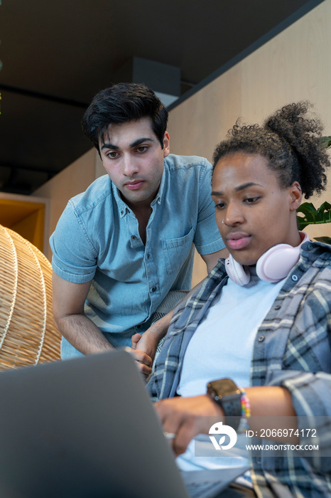 Serious colleagues looking at laptop in office