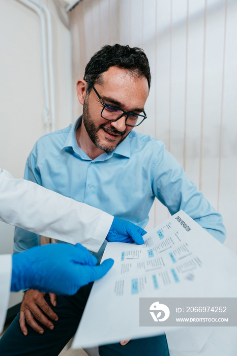 Middle age man sitting and talking with doctor at medical clinic for the treatment of infertility in man and woman. Expert consultation with a specialist during human semen analysis.