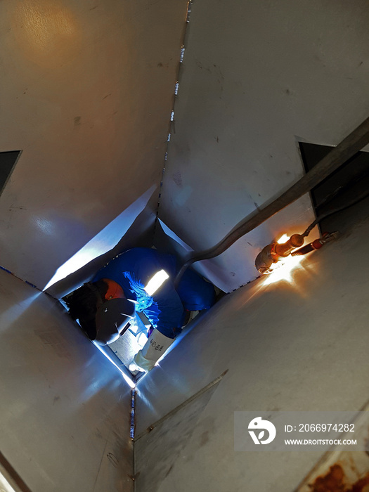 Welder working inside an hydraulic oil tank. Confined space works