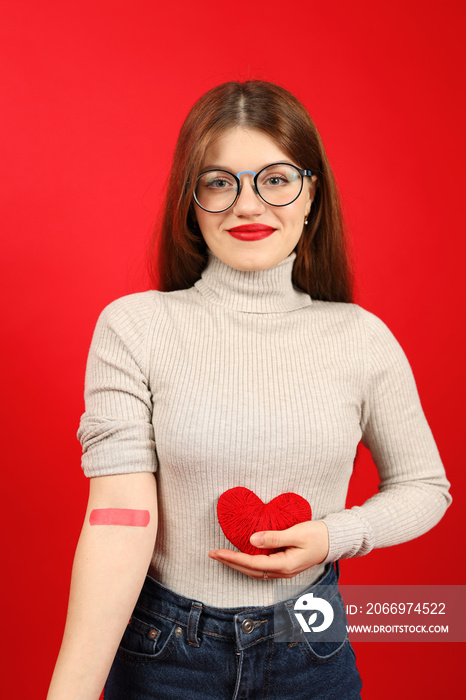 A volunteer after donating blood holds a heart in his hands and smiles, donor.