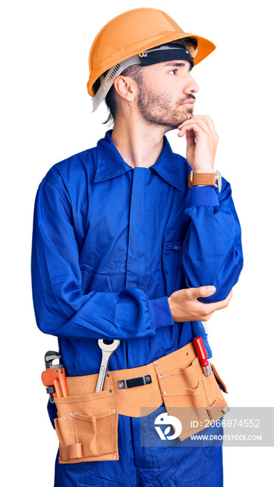 Young hispanic man wearing worker uniform with hand on chin thinking about question, pensive expression. smiling with thoughtful face. doubt concept.