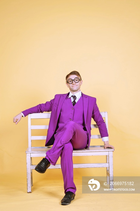Nerd businessman in purple suit sitting on bench