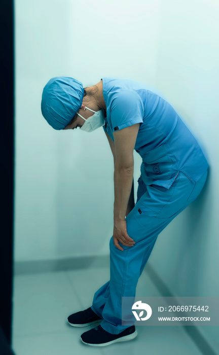 Medico latina con uniforme medico y mascarilla COVID cansada recargada en la pared del hospital  recuperandose