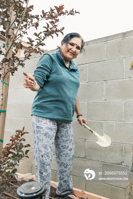 South Asian woman gardening in backyard