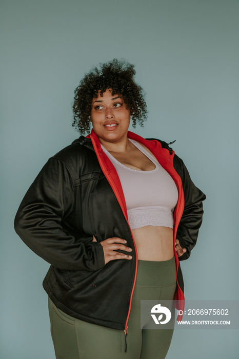 portrait of a plus size afro indigenous person with hands on hips looking away