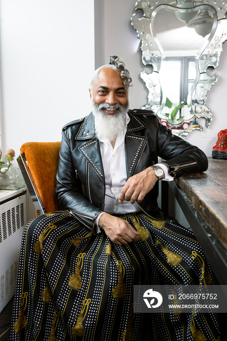 portrait of man with gray beard smiling wearing leather and skirt