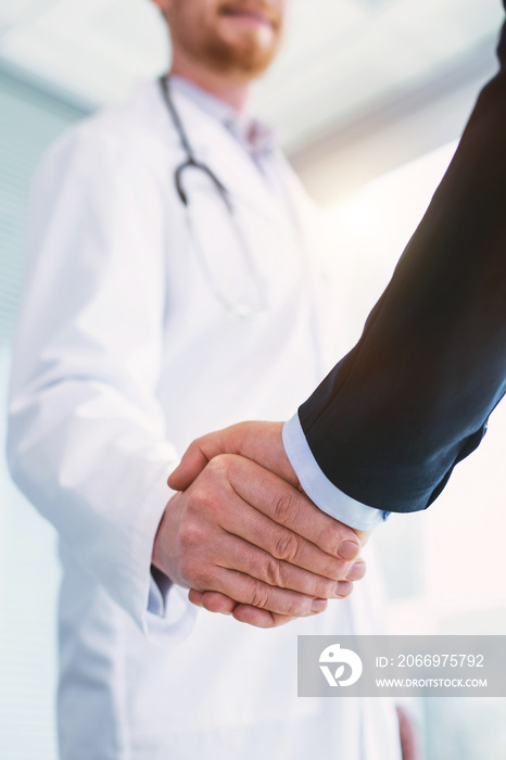 You are welcome. Inspired professional doctor wearing a uniform and shaking hands with a businessman