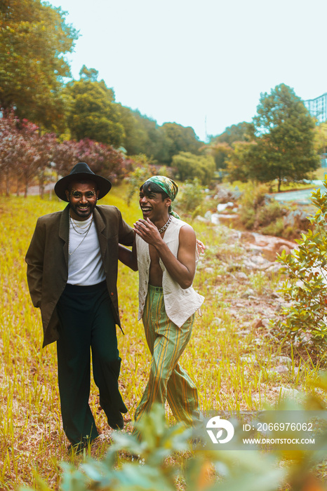 Two Malaysian Indian men surrounded by nature, walking in the grass, laughing together