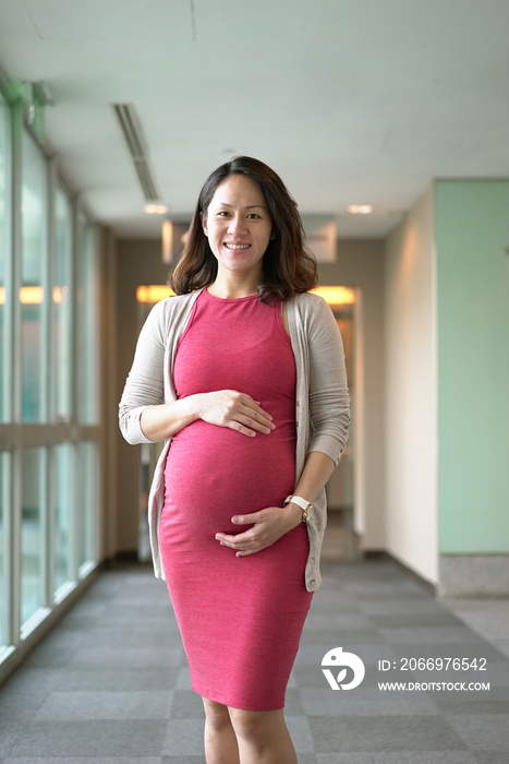 Happy delighted pregnant female office worker in her work environment