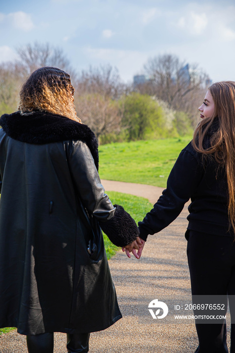 Lesbian couple walking in the park holding hands.