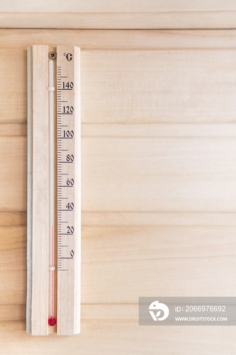 Wooden thermometer showing 28 degrees Celsius on a wooden wall