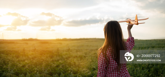 Silhouette of a girl at sunset in a field launching a toy airplane into the sky. Childhood dreams of flying. Walk in the summer in the evening in the field. Children concept