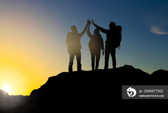 travel, tourism and hike concept - group of travelers with backpacks making high five on mountain top over sunrise background