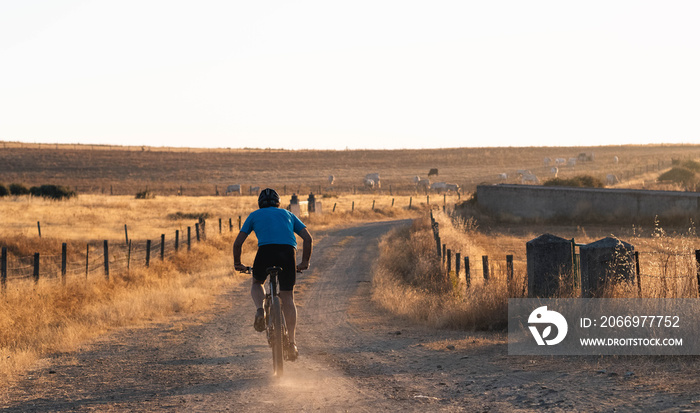 Mountain biker during a sunset on a dirt road. Personal improvement, cycling training and motivation