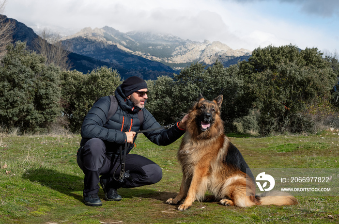 Man with his german shepherd dog in the mountains