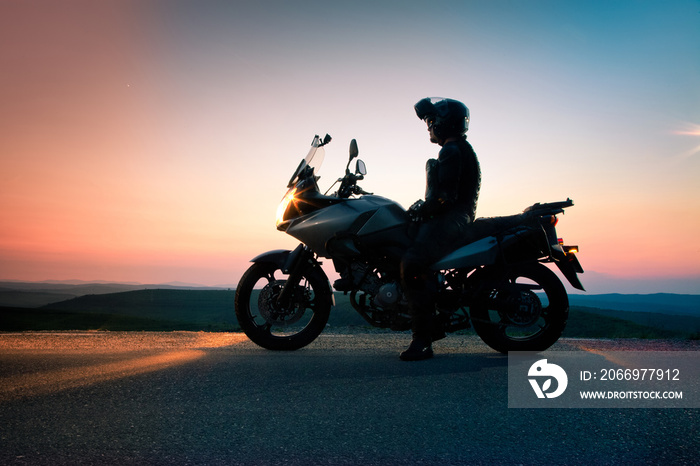 man on his motorbike admiring sunset - summer road trip - space for text