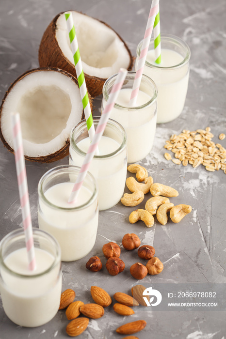 Vegan alternative nut milk in glass bottles on gray background. Healthy vegan food concept.