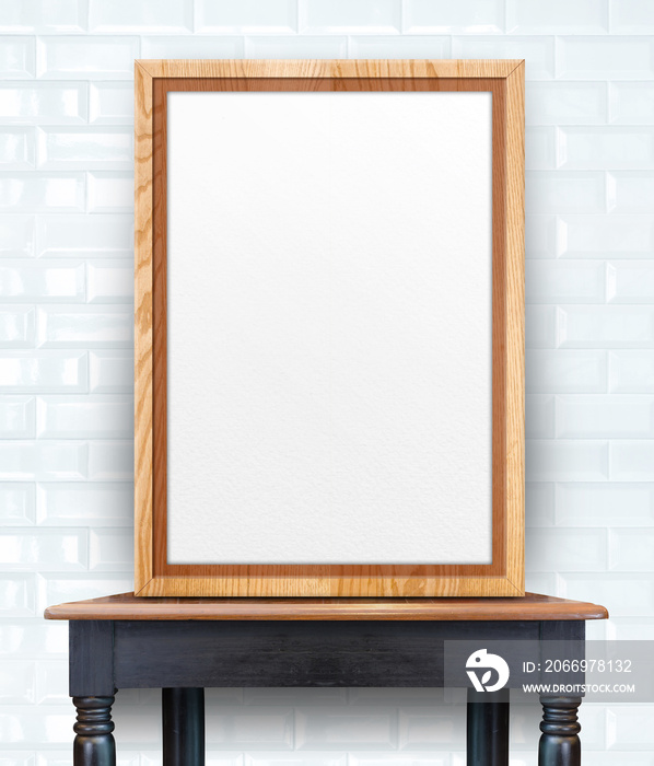 Blank wooden photo frame leaning at white glossy tile wall on vi