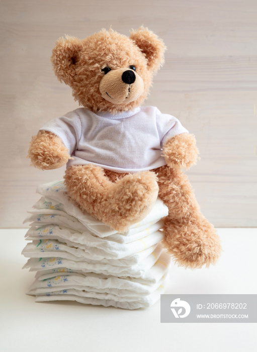 Baby diapers stack and teddy on white color floor