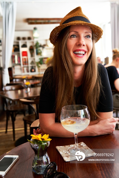 Woman in hat drinking gin tonic cocktail in cafe