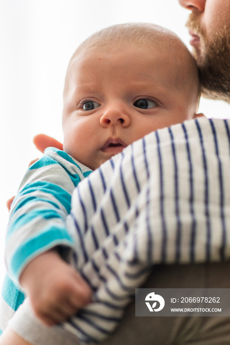 Little baby boy burps  and spits on the fabric diaper in the arms of his daddy. Baby with reflux held by his father.