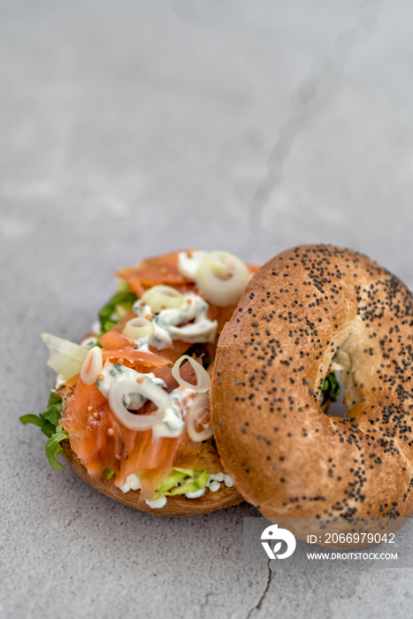 Salmon bagel with cream cheese, fresh herbs and veggies on a marble counter