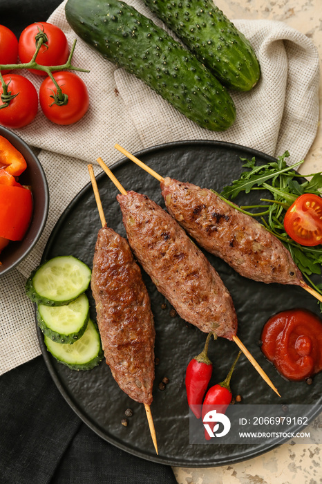 Plate of skewers with tasty lula kebab and vegetables on table